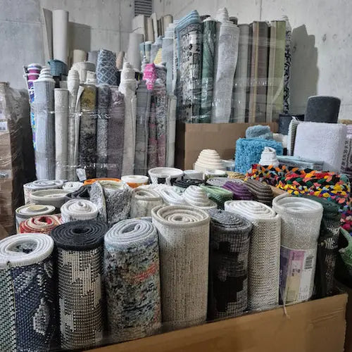 Collection of various rugs and carpet rolls in a storage area.
