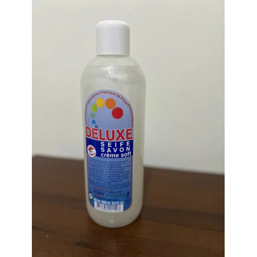 Bottle of Deluxe soap on a wooden surface with a white background