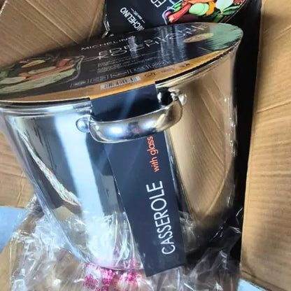 Stainless steel cooking pot with a visible brand tag on a cardboard surface