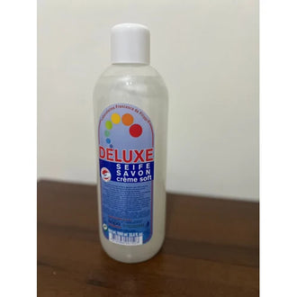 Bottle of Deluxe soap on a wooden surface with a white background