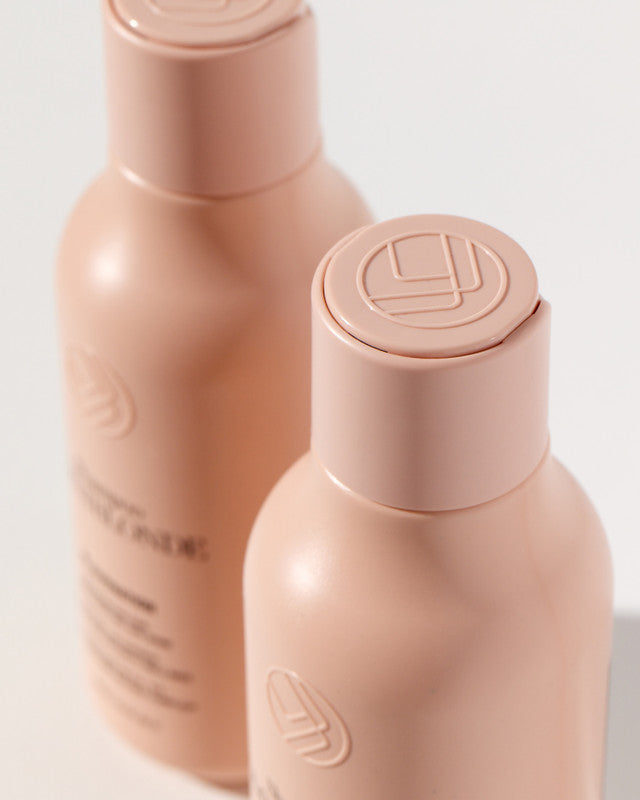 Two beige bottles with caps on a light gray background