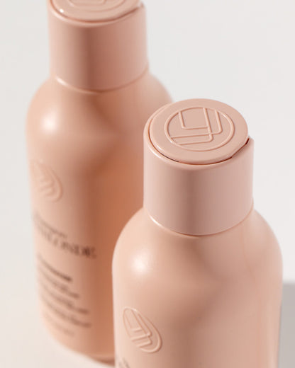 Two beige bottles with caps on a light gray background
