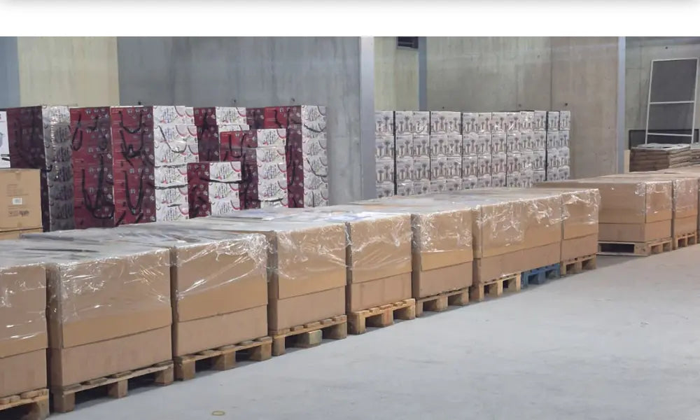 Stacks wholesale  boxes on pallets in a warehouse setting